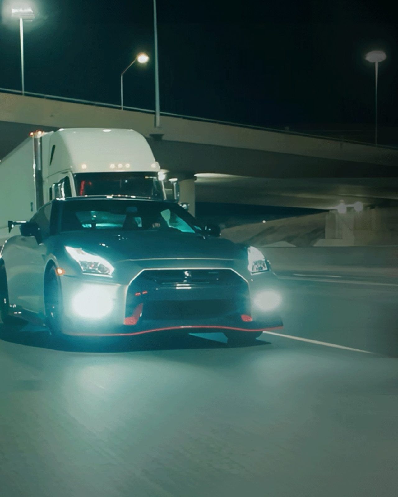 Nissan GT-R headlights on a lit highway at night