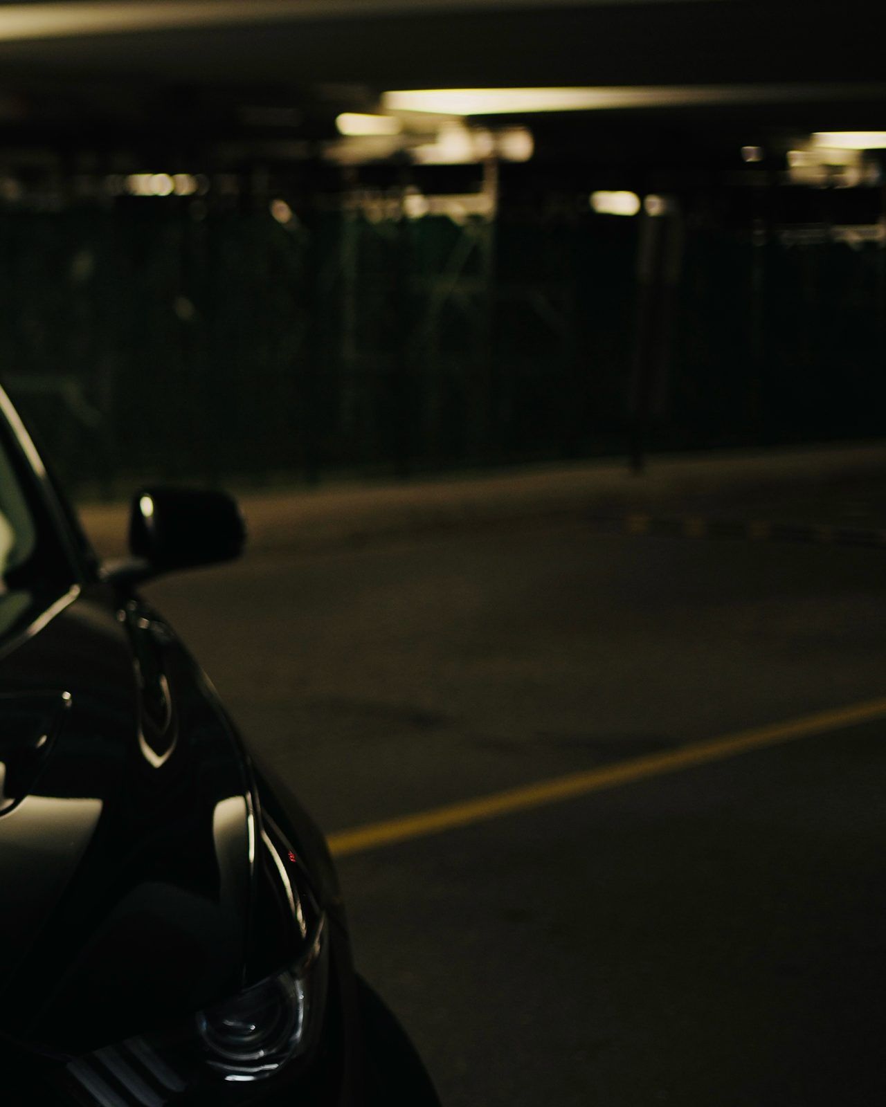 Close detail of a dark car in a parking garage at night