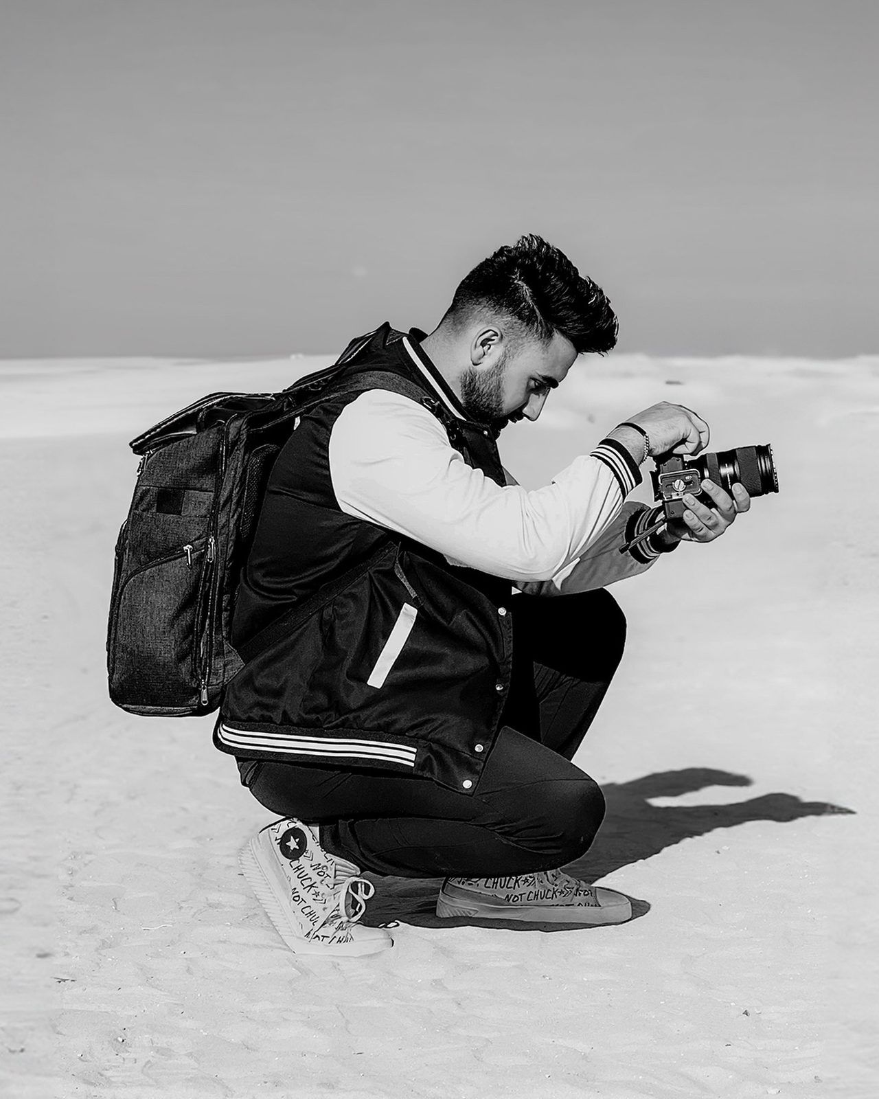 Jass Sangha crouching with a camera, shooting in the snow